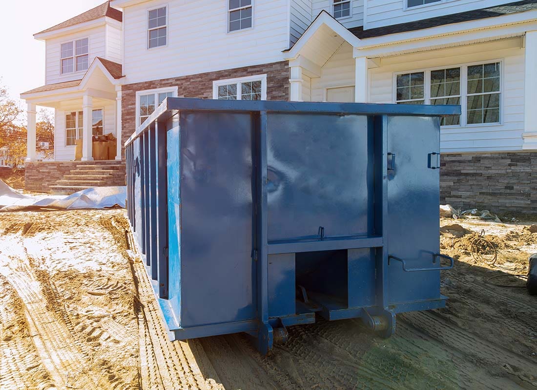 Dumpster Rental Insurance - Blue Dumpster in Front of a New Home for Waste and Construction Materials at a Construction Site