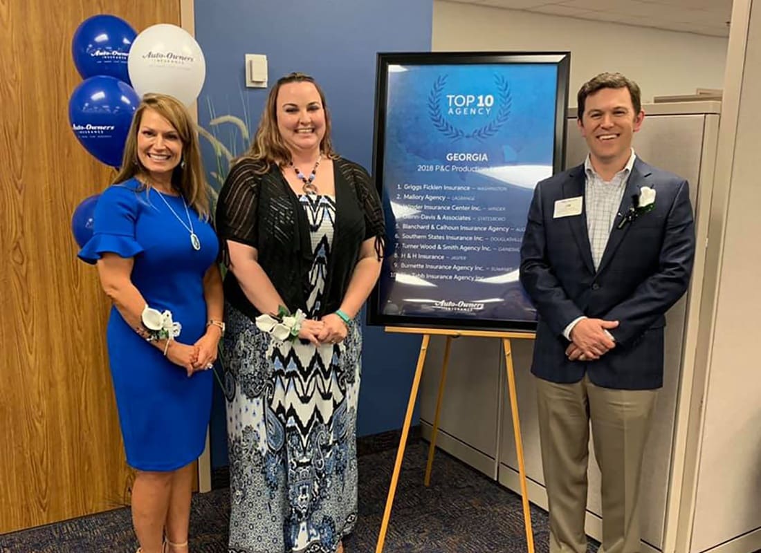 Contact - Smiling Team Members Jim Beth and Whitney from Southern States Insurance Standing Next to an Auto Owners Award During an Award Ceremony